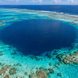 明るい青緑の浅瀬に囲まれた、濃い青色のブルーホール