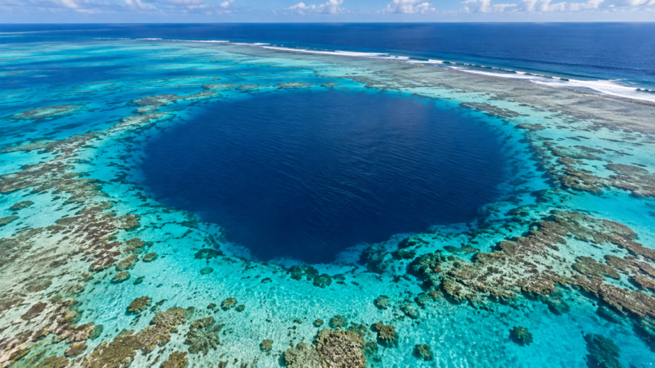 明るい青緑の浅瀬に囲まれた、濃い青色のブルーホール