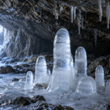 洞窟の床から上向きに育つ丸い先端の氷筍と天井から落ちる水滴