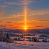 雪景色の夕空で、低い太陽の上に伸びるサンピラーのイメージ
